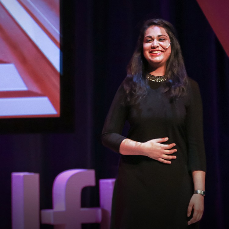 Mileha Soneji speaking on stage giving TED talk