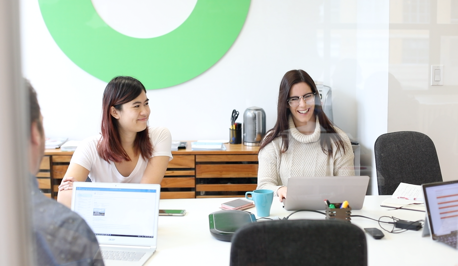 Two Flywheel employees smiling, working in the boardroom